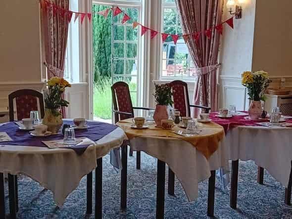 Sunlit dining room with bay windows opening to gardens