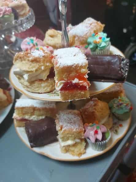 Tiered cake stand with scones, cream, and handcrafted pastries